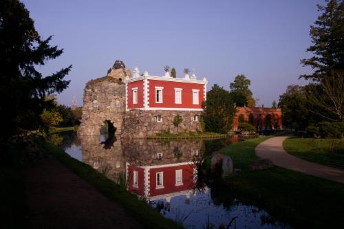 a large red house sitting on top of a lake at Hotel Zum Stein Wellness & Genuss Resort in Oranienbaum-Wörlitz
