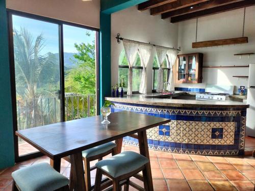 a kitchen with a wooden table and a large window at Casa Pajaros Balcony in Cruz de Huanacaxtle