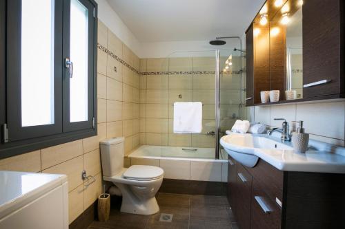 a bathroom with a toilet and a sink and a tub at Villa Athinais in Lixouri