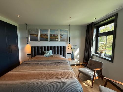 a bedroom with a large bed and a chair at Urk-Stay in Tollebeek