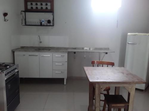 a kitchen with a wooden table and a refrigerator at Pouso Vista da Serra in São João del Rei
