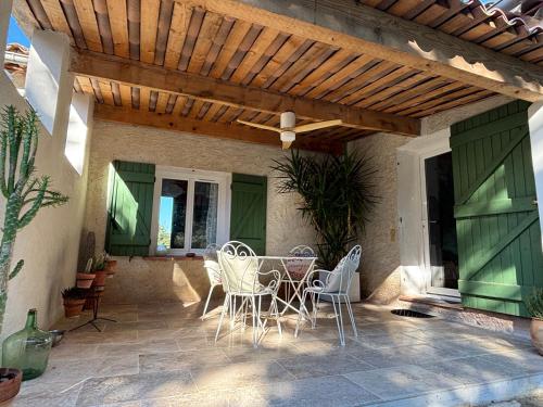 un patio avec une table et des chaises sous une pergola en bois dans l'établissement Le clos Gaya, à Correns