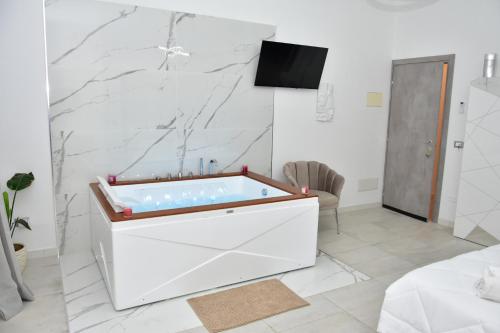 a bath tub in a white room with a tv at Yllen Rooms in Avola