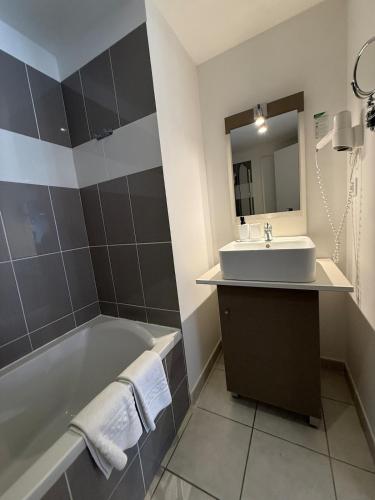 une salle de bain avec une baignoire, un lavabo et un miroir dans l'établissement T2 Cap Agde Terrace Piscine, au Cap d'Agde
