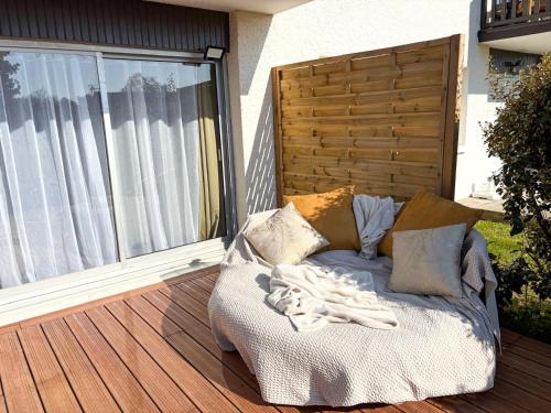- un canapé installé sur une terrasse couverte à côté d'une fenêtre dans l'établissement Charmant cocon avec terrasse en RDC proche plage, à Cabourg