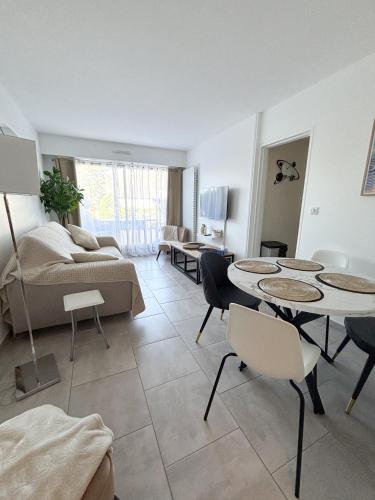 un salon avec un canapé, une table et des chaises dans l'établissement Charmant cocon avec terrasse en RDC proche plage, à Cabourg