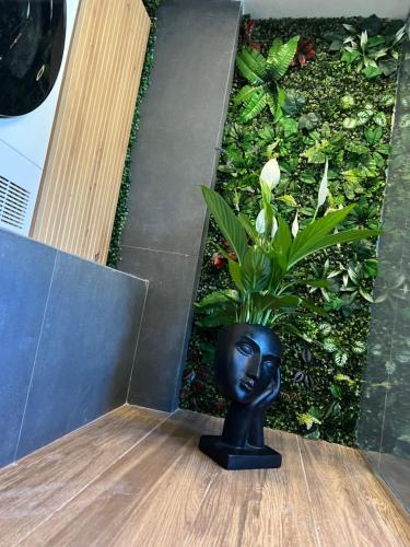 a black head vase sitting on a table with a plant at Glow&Go Vlora in Vlorë