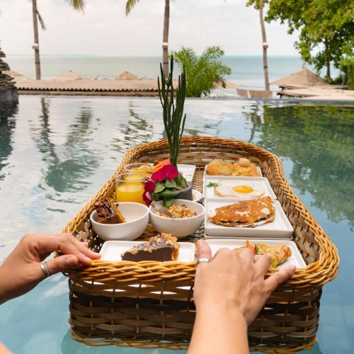 ein Tablett mit Essen in einem Korb neben einem Pool in der Unterkunft Apenunga Eco Hotel in Jericoacoara