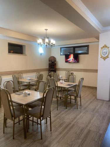 ein Esszimmer mit Tischen, Stühlen und einer Uhr in der Unterkunft DECCA Hotel in Yerevan