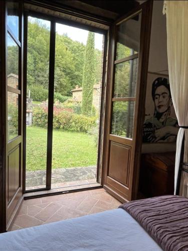 a bedroom with a large glass door to a garden at Casal'terra - Il Fosso in Salaiola