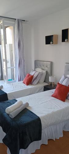 Cette chambre comprend 3 lits avec des oreillers rouges. dans l'établissement Appartement vue mer et panoramique, 2 chambres, 3 lits, à Nice