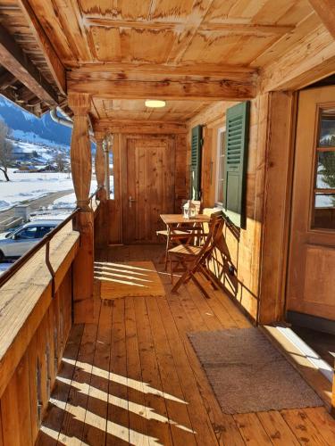 a wooden porch of a cabin with a table at Burgbühler Guesthouse in Lenk