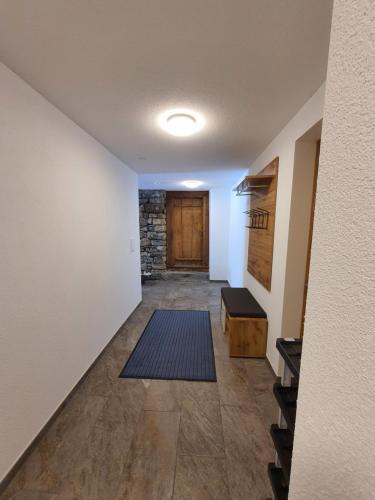 a hallway with a door and a room with a rug at Burgbühler Guesthouse in Lenk