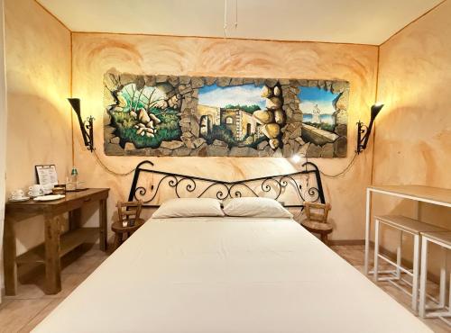 a bedroom with a bed with a painting on the wall at B&B Sa Bèrtula in La Maddalena