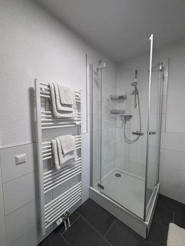 a white bathroom with a shower and towels at Terrace 24 Urban Stay in Villingen-Schwenningen
