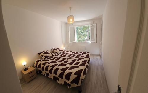 a bedroom with a black and white bed and a window at Appartement proche centre-ville et plages in Cavalaire-sur-Mer