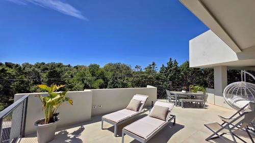 a patio with chairs and tables on a balcony at Shati Luxury - New, Heated Pool, Sea view Near beach in Fontane Bianche