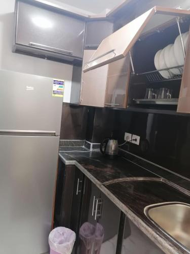 a small kitchen with a sink and a refrigerator at شالية فندقي غرفة ورسيبشن وحمام ومطبخ مكيف بالكامل بورتو سعيد Porto Said in Port Said
