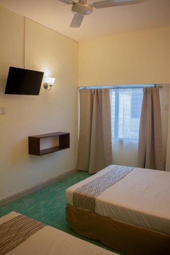 a bedroom with a bed and a tv and a window at Nuevo Paris Hotel in Mérida