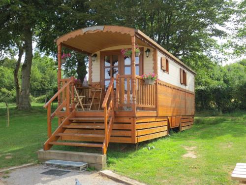 une petite maison avec une terrasse couverte et un escalier dans l'établissement les roulottes des marquets, à Bourthes