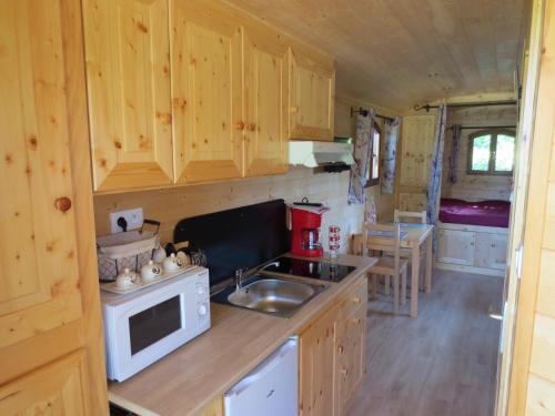 une cuisine avec des armoires en bois, un évier et une cuisinière dans l'établissement les roulottes des marquets, à Bourthes