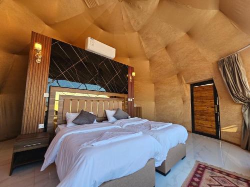a bedroom with a large bed with a wooden ceiling at Wadi Rum Grand in Wadi Rum