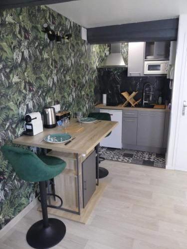 - une cuisine avec une table en bois et un mur vert dans l'établissement L'Oasis Amiénoise - Le Quai Amiénois, à Amiens