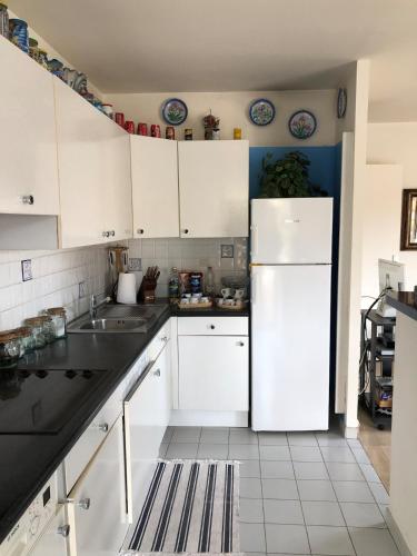 une cuisine avec des armoires blanches et un réfrigérateur blanc dans l'établissement La Villa Rimbaud, à Cannes