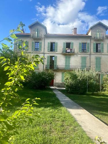 une grande maison blanche avec une cour en gazon devant elle dans l'établissement Escapade Provençale T2, à Digne-Les-Bains