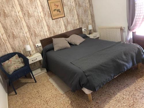 a bedroom with a large bed and a chair at Hostal Braseria Missamaroi in Tivissa
