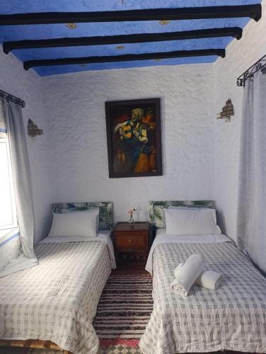 a bedroom with two beds and a painting on the wall at hotel dar lalla khadouj in Chefchaouene