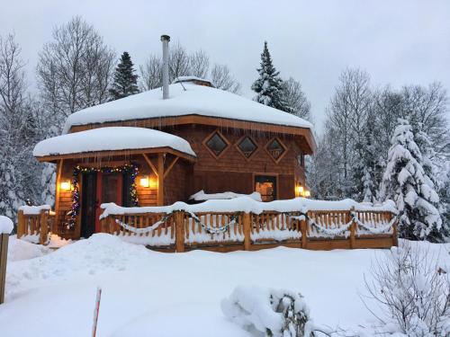 Carrollにある1800OR Unique 'yurt' home in Bretton Woods 1 mi to skiing firepit foosball beach Hot tubの雪の中のログキャビン(ポーチ付)