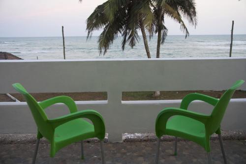 two green chairs sitting next to a table overlooking the ocean at Atlantic View Apartment in Takoradi