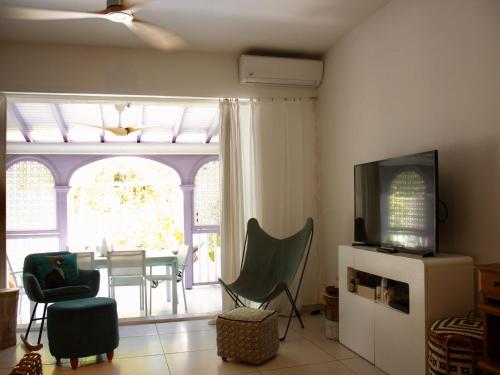 オリエントベイにあるKazamwen, maison à Orient bay 2 chambres, piscine résidence et plage à 2 minutesのテーブルと椅子とテレビのあるリビングルーム