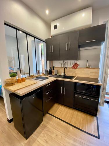 - une cuisine avec des placards noirs et un évier dans l'établissement Charmant Petit studio proche Centre et Plage, à Banyuls-sur-Mer