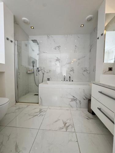 La salle de bains blanche est pourvue d'une douche et d'une baignoire. dans l'établissement Luxury appartement 165m2 Paris 16 Victor Hugo Etoile AC, à Paris