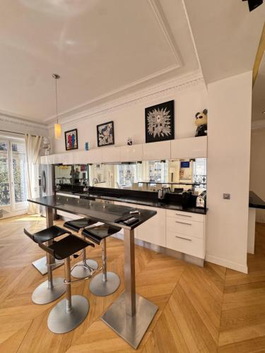 une cuisine avec un comptoir noir et des chaises noires dans l'établissement Luxury appartement 165m2 Paris 16 Victor Hugo Etoile AC, à Paris