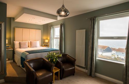 a bedroom with a bed and two chairs and a window at Pentire Newquay Cornwall Hotel in Newquay