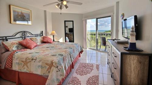 Tavernierにある2306 Ocean Pointe Suitesのベッドとテレビとバルコニーのある寝室