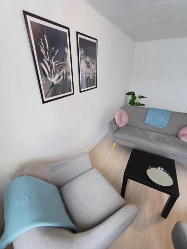 a living room with a couch and a chair at Bright Double Room with Free Parking in Hjørring