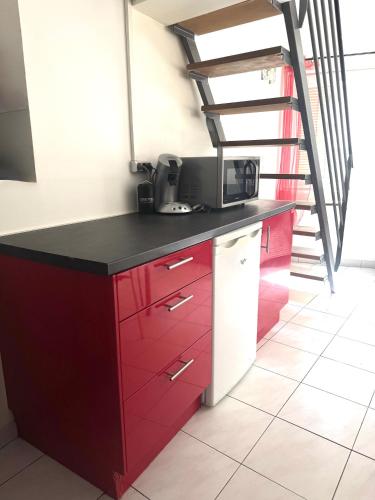 une cuisine avec des placards rouges et un escalier dans l'établissement Centre-ville Avignon - Duplex - Terrasse privée, à Avignon