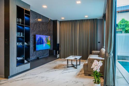 ein Wohnzimmer mit Sofa und Fernseher in der Unterkunft Pool Villa Sura Designer in Nong Prue