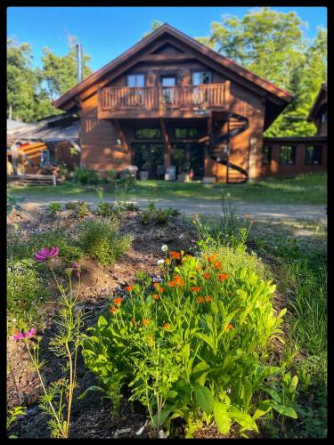 a log cabin with a flower garden in front of it at gite comme un accord in Saint Mathieu Du Parc