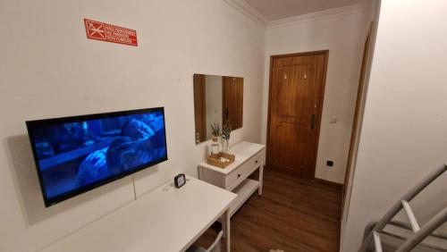a living room with a flat screen tv on a wall at Guest House da Mata2 in Póvoa de Varzim