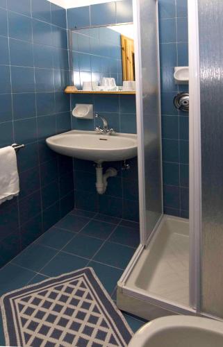 a blue tiled bathroom with a sink and a shower at Albergo Adele in Bormio