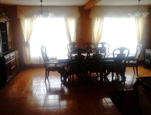 Un comedor con mesa y sillas y ventanas. en Hermosa casa en Valdivia, en Valdivia