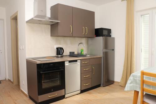 une cuisine avec une cuisinière et un réfrigérateur dans l'établissement Apartments and rooms by the sea Kukljica, Ugljan - 24327, à Kukljica