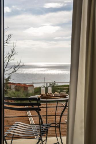 a table and chair on a balcony with a view of the ocean at Viento Luxury Apartments in Plomarion