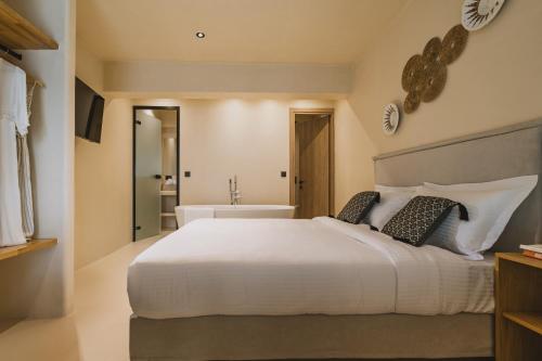 a bedroom with a large white bed and a bath tub at Viento Luxury Apartments in Plomarion