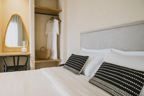 a bedroom with a white bed with a mirror and a chair at Viento Luxury Apartments in Plomarion